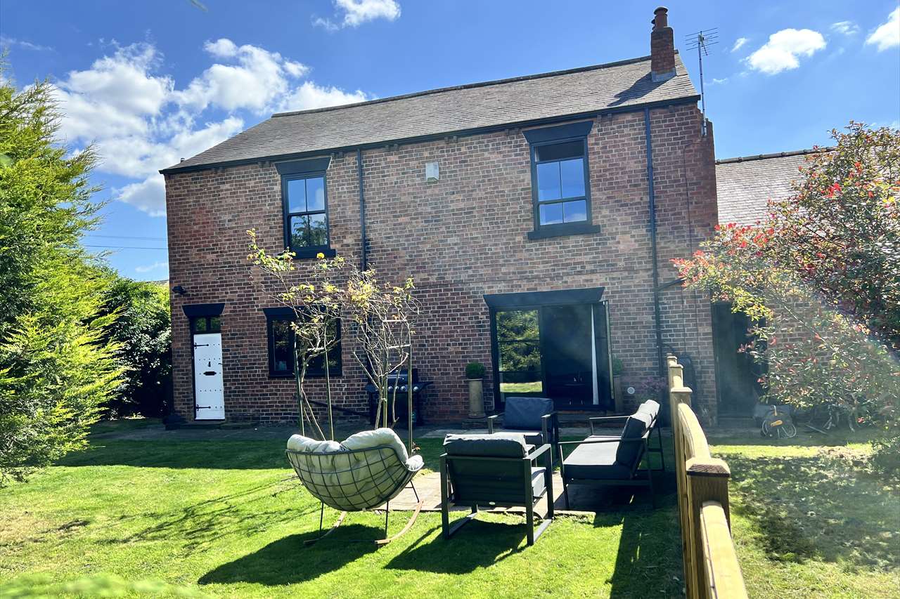 The back of our house seen from the garden, with outdoor seating on the lawn